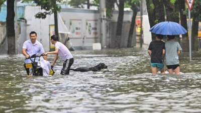 台风“烟花”首次登陆后，为浙江带来强风暴雨，多地出现灾情，这是宁波的灾民在水淹过膝的积水中涉水而行。（图取自法新社）