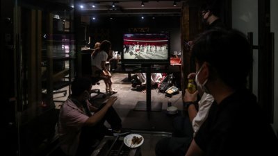 东京奥运开幕式为了防疫，不开放民众入场，当晚有支持者在主场馆附近的一家餐馆，透过电视实况转播观看开幕典礼。（法新社）