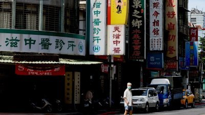 台湾疫情严峻、没有减缓趋势，民众重症及死亡率不断攀高，死者年龄层也偏高，周六新增37人死亡，改写单日新高记录。这是台北市一名戴口罩的老人走在街道上。（图取自路透社）