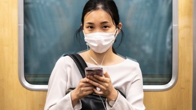 新冠肺炎疫情颠覆了人们的生活。有日媒指日本去年新生儿人口减少，仅是疫情影响的开始，今年影响将更明显。图为东京一名戴口罩的女性在列车车厢内使用手机。（图取自法新社）