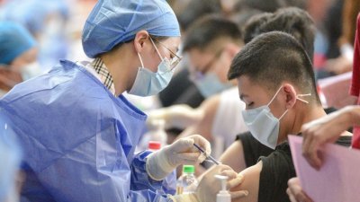 中国广西壮族自治区柳州市的广西科技大学体育馆内，医护人员为师生接种新冠疫苗。（图取自中新社）