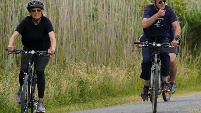美国总统拜登（右）当地时间周四和第一夫人吉尔在家乡特拉华州骑脚车进行休闲活动时，向媒体记者和围观者竖起拇指称好。（图取自路透社）