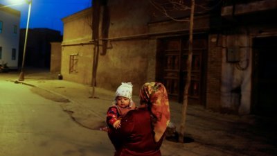德国学者在最新报告指出，中国生育控制政策可能使维吾尔族及新疆南部少数族裔的新生儿人数大幅减少。中国官方驳斥报告内容。图为新疆维喀什老城，一名妇女夜里抱著一个孩子的档案照。（图取自路透社）