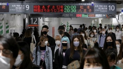 日本东京的火车站内，通勤民众都戴上口罩防疫。（图取自路透社）