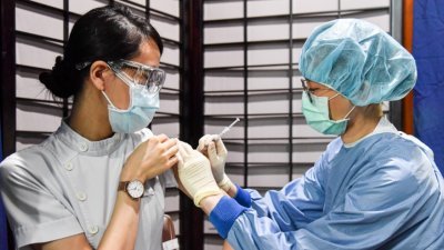 台北慈济医院周四为医护人员施打莫德纳疫苗，一名护理人员配戴护目镜接种疫苗。（图取自中央社）