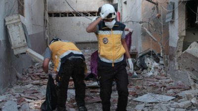 叙利亚北部城市阿夫林市内多处地点遭炮弹袭击，多数死者是遭袭击的一家医院内的人员，多人伤势严重。这是叙利亚公民防御组织“白头盔”的人员在遭袭医院进行救援工作。（图取自法新社）
