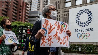 日本新冠肺炎疫情未止，东京都近日有新增确诊病例数居高不下的倾向，反对举行东奥的人士周六前往东京都政府大楼参加示威抗议。（图取自法新社）