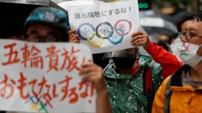 一群反对政府坚持在疫情期间举办奥运会的民众，周六手持标语走上东京街头游行。（路透社）
