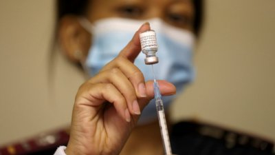 非洲过去一周的新冠肺炎确诊病例增加52%，死亡人数增加32%，疫情仍在急速升温。图为南非约翰内斯堡郊外的蒙西维尔老年护理中心，医务人员手持一小瓶的美国辉瑞药厂（Pfizer）和德国生物科技公司BioNTech共同研发的新冠疫苗。（路透社档案照）