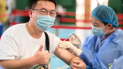 在内蒙古呼和浩特市一新冠肺炎疫苗接种点，一位年轻人上周六接种疫苗时竖起大拇指。（图取自中新社）