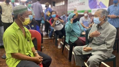 马哈迪（右）慰问其中一名在阿希化礼堂准备接种疫苗的民众。