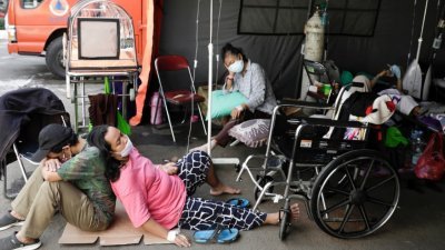 西爪哇省勿加泗的一所政府医院，在急诊室外搭建帐篷收治新冠肺炎患者，但病床仍不够用，有的患者只能隔著纸皮坐在地上吊点滴治疗。（图取自路透社）