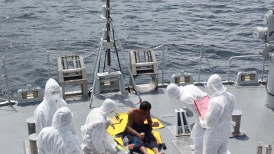 海军人员将渔民救上船后，也为对方进行新冠病毒检测。