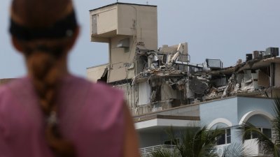 迈阿密海滩北部公寓局部倒塌事故，至今踏入第3天，找到更多生还者的希望愈来愈渺茫。有报告曝光指工程师3年前就曾经警告大楼结构有问题，图为当地一名女子遥望著塌楼的损毁结构。（图取自路透社）