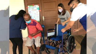 廖彩彤（右2）在疫苗中心协助一名民众使用轮椅。
