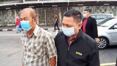 被告杨亚来（左）在反贪会官员的陪同下，周三上庭面控。