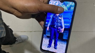 27岁的塔彭拒绝服从上司的命令后逃往印度，他在印缅边境的一个小镇受访时，向记者展示他身穿警察制服的照片。（路透社）