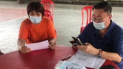 苏建祥（右）为金宝县的民众登记接种新冠病毒疫苗。