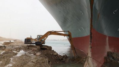 长荣巨型货轮“长赐”号卡在苏伊士运河中已3天，这是一辆挖土机在清淤近3天后有所成果，目前已让部分船头“重见天日”。（图取自苏伊士运河管理局/路透社）
