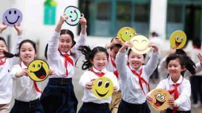 江苏省扬州市汶河小学的学生们在“笑迎世界微笑日”活动中手举笑脸卡做游戏。