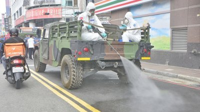 台湾新北市周五全面消毒环境，阻断新冠肺炎传播链。图为国军化学兵群支援三重区消毒，沿途喷洒药剂。（图取自中央社）