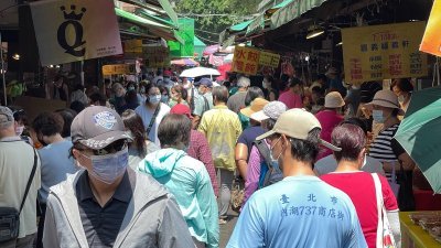 台湾新冠肺炎疫情大爆发，台北市内湖传统市场周六上午出现采买人潮，市场民众配合防疫都戴上口罩。（图取自中央社）