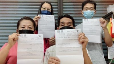 陈国明（左2）与家人展示新冠肺炎筛检报告，强调没有家庭成员确诊。