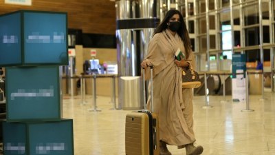 沙地阿拉伯周一起允许已对新冠肺炎具有免疫力的公民出国旅行。这是一名当地女子抵达利雅得哈立德国王国际机场后，推著行李箱走向登记柜台。（图取自路透社）