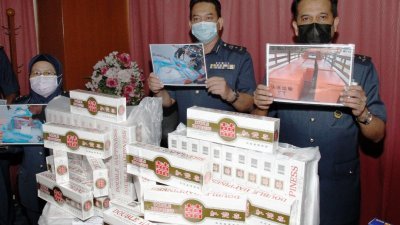 萨扎里莫哈末（右）与关税局官员展示被当局起获的逃税香烟及用来藏匿逃税烟的鱼箱照片。