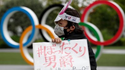 民众在日本奥林匹克委员会总部外抗议，反对在新冠肺炎疫情持续的情况下举办奥运会。（图取自路透社）
