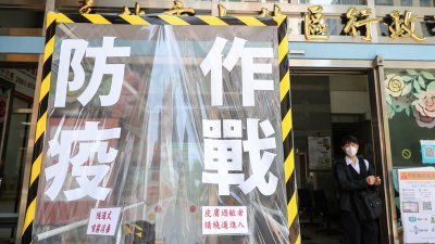 台湾本土疫情升温，台北市士林区行政中心门口设置隧道式喷雾消毒通道，上面写著“防疫作战”4字，提醒民众防疫不能松懈。-中央社-