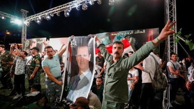已经掌权21年的巴沙尔再次连任叙利亚总统，他的支持者在选举成绩公布前，就已聚集在首都大马士革，拿著他的肖像和国企庆祝。（图取自路透社）