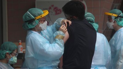台北市立联合医院阳明院区周日上午施打疫苗，医护人员为民众施打疫苗。（图取自中央社）