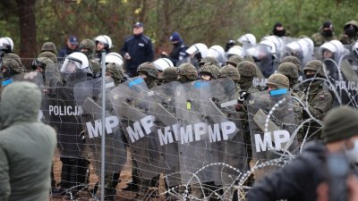 大批移民聚集在白罗斯与波兰边境，波兰执法人员和边防警卫站在带刺铁丝网围栏旁。（图取自BelTA/路透社）