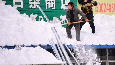 中国辽宁省沈阳市自周日（7日）起至周二（9日）降下暴雪，累积降雪量高达51毫米。图为民众清除屋顶上的厚雪。（图取自中国日报/路透社）