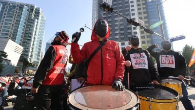 上月20日，韩国13个城市的约8万多名韩国工会总联盟成员举行罢工集会，要求韩国政府取消非正式员工岗位，改善工作条件，提高最低工资等。许多工人身穿Netflix热播剧《鱿鱼游戏》服装抗议，还在现场跳舞奏乐。（图取自韩联社\路透社）