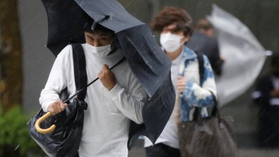 日本全面解除紧急事态宣言，民众恢复正常生活，但受到台风搅局，东京市民撑著雨伞，顶著风雨在街上行走。（图取自路透社）