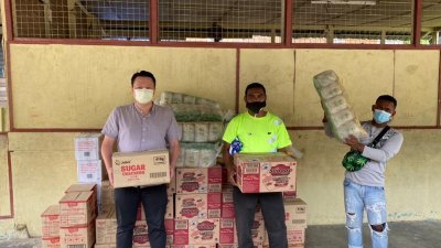 张玉刚（左起）移交80份粮食包给正在落实强化行动管制令的瓜拉波原住民村（Kpg Kuala Boh）村长诺丁。