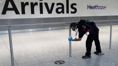 英国伦敦希思罗机场的工作人员，在入境大厅擦拭围栏消毒。（图取自路透社）