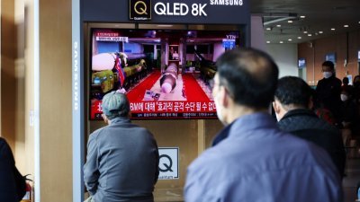 在首尔火车站，民众周二看著电视播报有关朝鲜在东部海域发射弹道导弹的新闻画面。（图取自路透社）