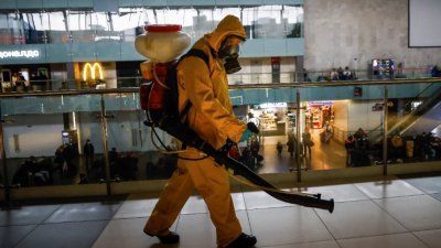 穿著个人防护装备的工作人员，在莫斯科的列宁格勒火车站消毒。（图取自路透社）