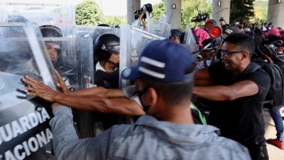 数千名移民离开墨西哥南部，来到塔帕丘拉城试图突破警卫军防线，北上前往首都墨西哥城，与警卫军发生肢体冲突。（图取自路透社）