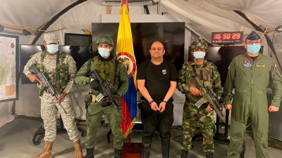 哥伦比亚政府当地时间周六发布该国头号毒枭奥托尼尔双手上铐、被军人包围的照片。（哥伦比亚军队/路透社）