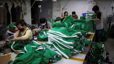 韩剧《鱿鱼游戏》风靡全球，连带也带旺剧中的道具和服饰。图为韩国首尔一家服装厂的工人们，赶制剧中爆红的绿色运动服。-路透社-