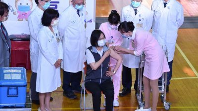台湾总统蔡英文（坐者）9月30日一早前往台大医学院体育馆，挂号经医生问诊后，卷起左边上衣袖子、施打第2剂高端疫苗。（图取自中央社）