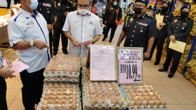 张发虎（右）在莫哈末海鲁安华陪同下，检查超市售卖的鸡蛋价格。