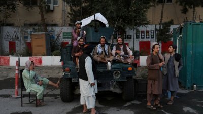 在喀布尔的一个主要城市广场，一班塔利班士兵坐在车上休息。（图取自路透社）