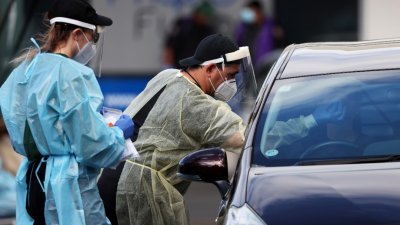 奥克兰民众坐在车上让医务人员采样，进行新冠病毒检测。（图取自路透社）