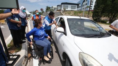 阿末费沙（右）巡视设立于新山拉庆游泳中心的残疾人士得来速（Drive thru）疫苗接种中心。左为莱斯阿迪峇。