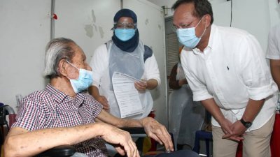 哈斯尼（右）在疫苗接种外展活动上，问候一名接种疫苗的年长者。